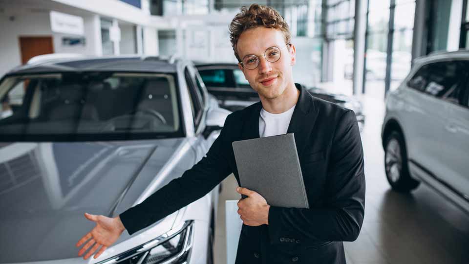 Ein Verkäufer zeigt auf ein Auto und erklärt dem Kunden die Konditionen beim Auto verkaufen Forchheim